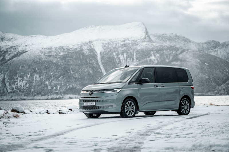 Volkswagen Multivan stoi na ośnieżonej drodze na tle gór.