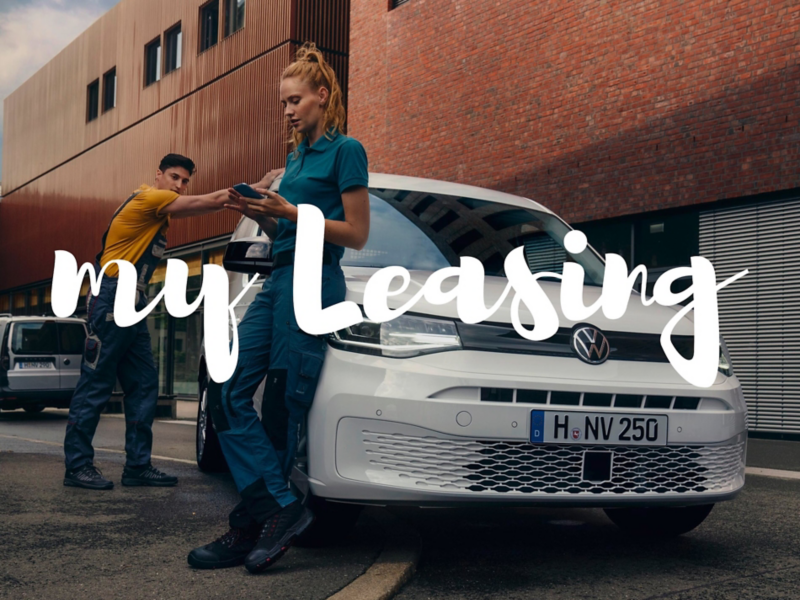Una mujer usando un teléfono móvil junto a un hombre, vestidos con uniforme de trabajo apoyados en un VW Caddy Cargo.