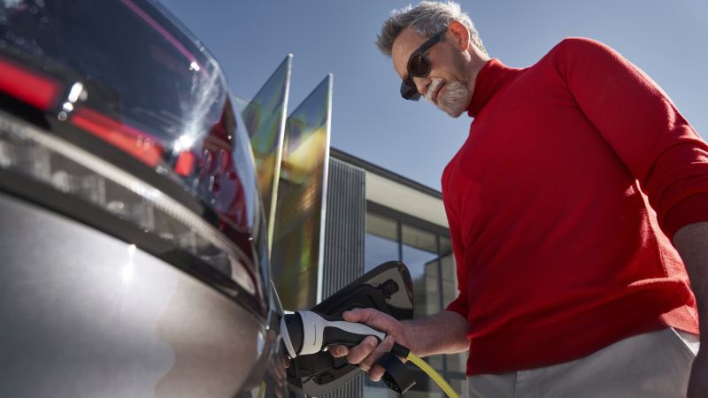 Person charging an electric vehicle using a Plug&Charge connector.