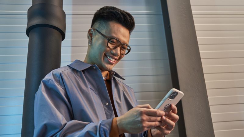 Un homme souriant utilise l'application myVW sur son téléphone.