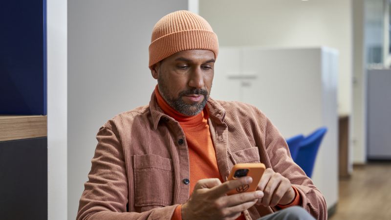 Un homme avec un bonnet orange regarde un téléphone