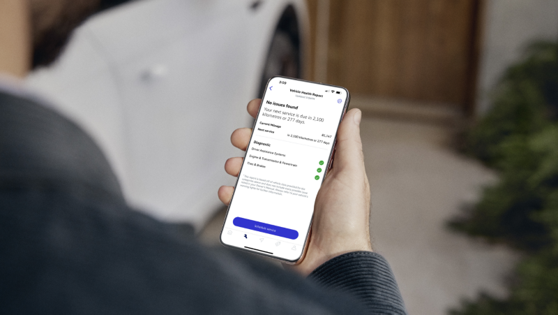 Une personne tient un téléphone affichant un rapport de santé du véhicule.
