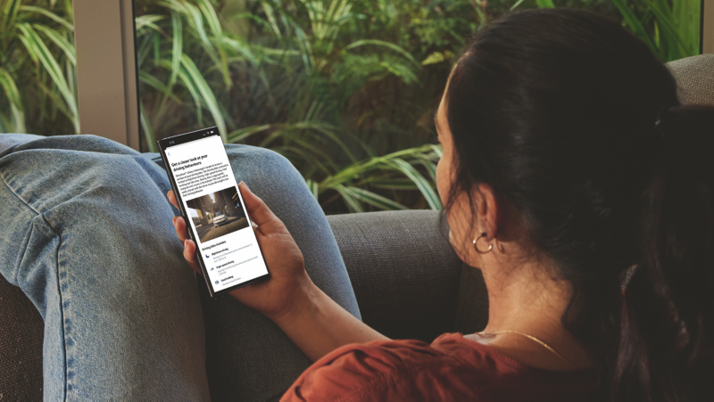 A woman on a sofa is looking at a phone screen.
