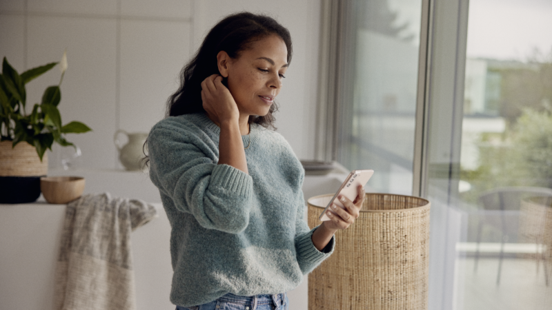A woman is holding a smartphone indoors.