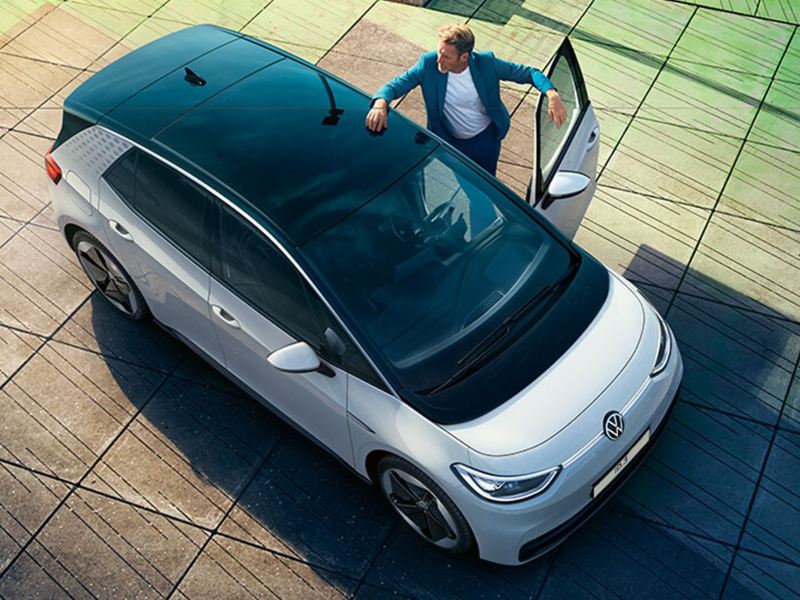 A person standing by a white VW ID.3 with the drivers door open