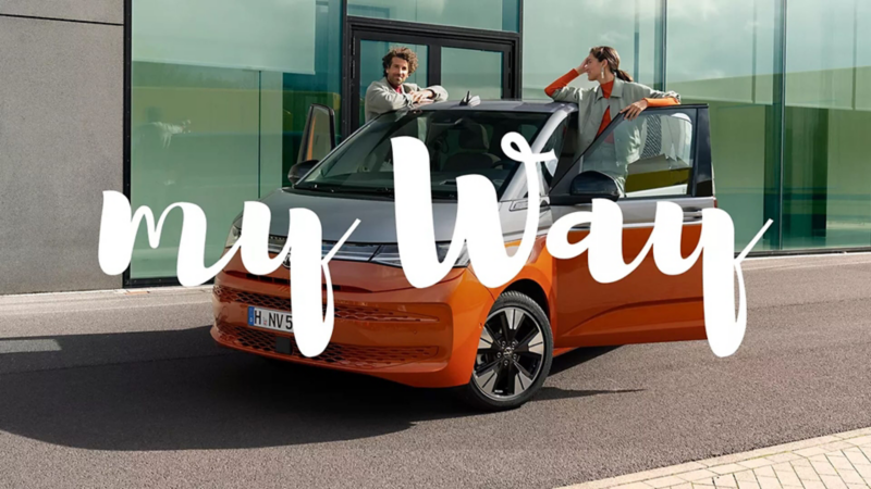 Dos personas con una furgo Volkswagen bicolor y el rótulo de My Way