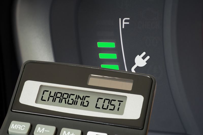 Nahaufnahme eines Taschenrechners, der den Preis einer Ladung verdeutlichen soll. Im Hintergrund ist die Ladestatus-Anzeige eines Elektroautos zu sehen.