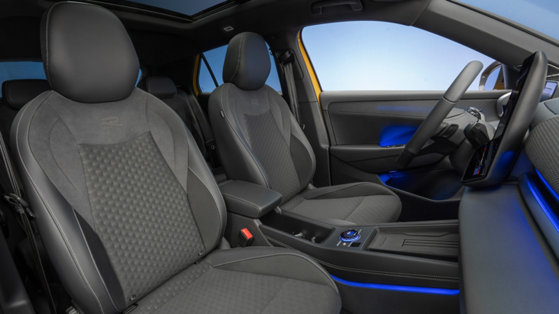 Vorderer Innenraum eines VW T-Roc mit Fahrer- und Beifahrersitz, Mittelkonsole und blauer Ambientebeleuchtung.