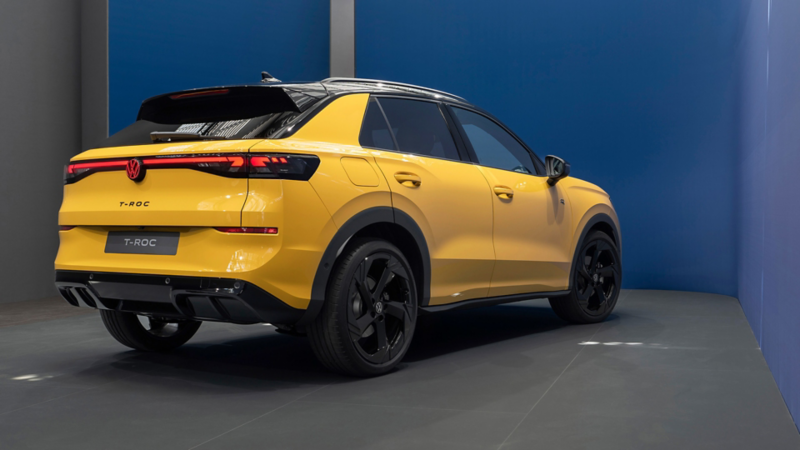 Rückansicht eines gelben VW T-Roc, fotografiert schräg von hinten, mit schwarzem Dach und roten Rückleuchten.
