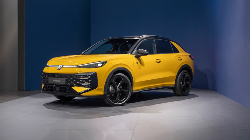 Ein gelber VW T-Roc steht schräg von vorne in einem Studio mit blauem Hintergrund.