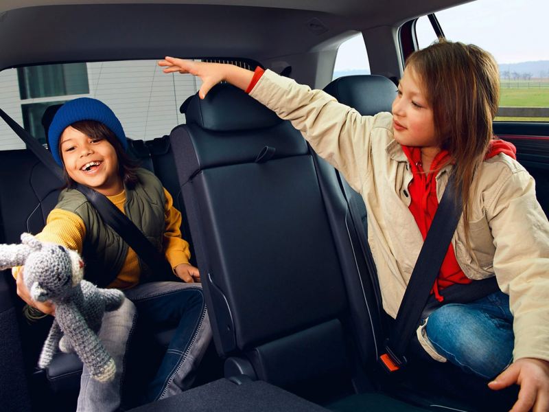 Two children sit in the interior of a Tiguan Allspace Elegance: a girl in the second row of seats, a boy in the third row. 