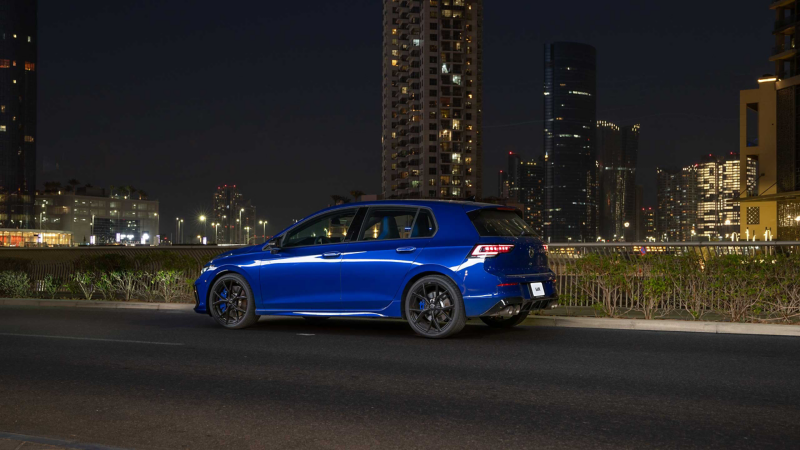 Man leaning against the front of a VW Golf R with illuminated LED crossbar