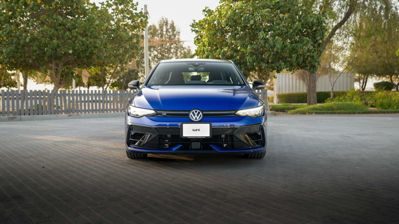 Man leaning against VW Golf R, focus on rear view