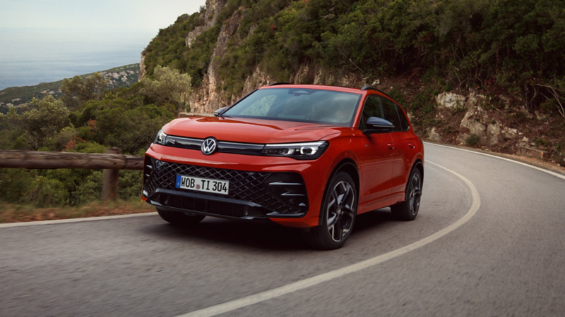 A red VW Tiguan driving down a mountain road