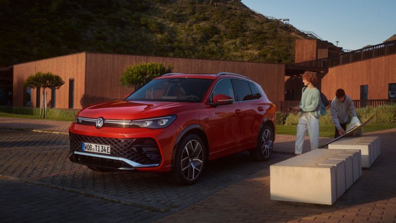 A red VW Tiguan in a parking bay with a mother and child approaching the car