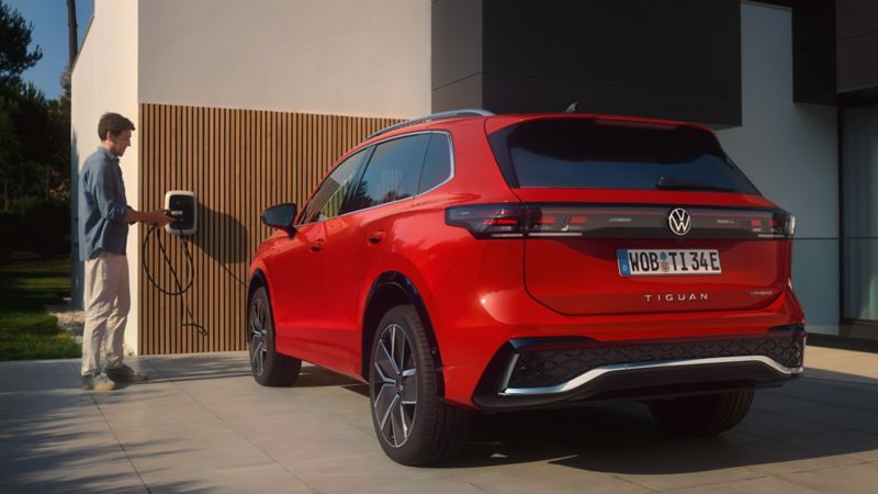 a new red Tiguan with a man standing by the charge pod