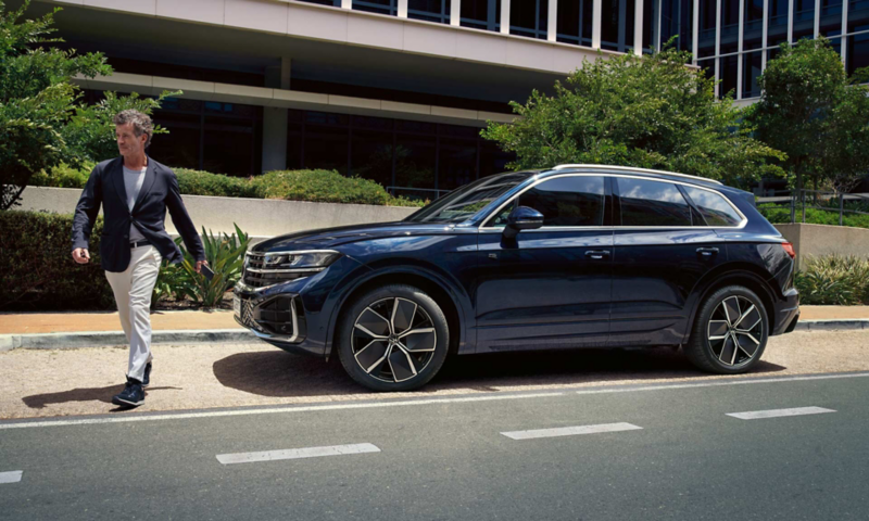 A Touareg parked outside an office building with the owner walking away from the car