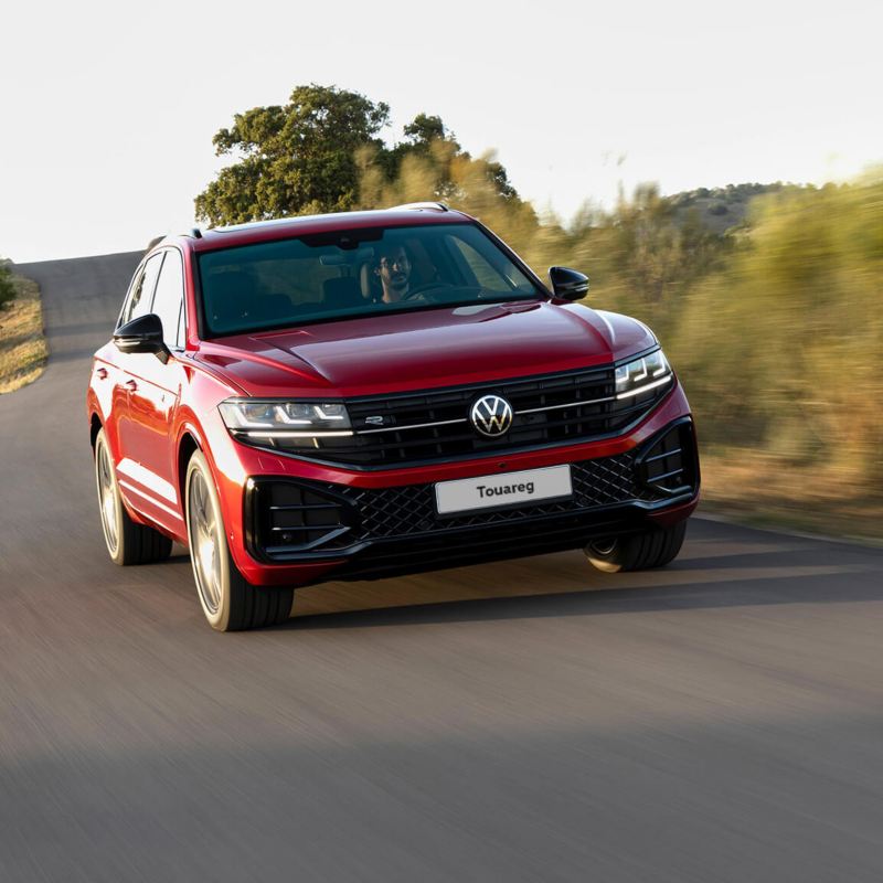 A red Volkswagen Touareg driving in the countryside