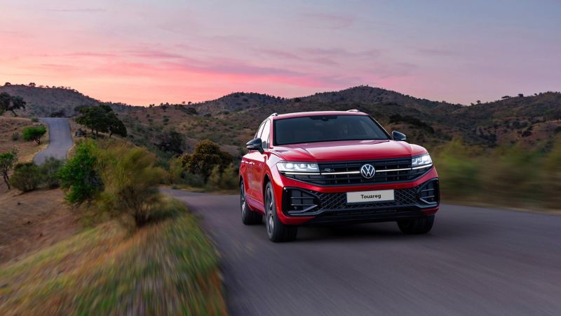 a red Touareg driving along a country road 