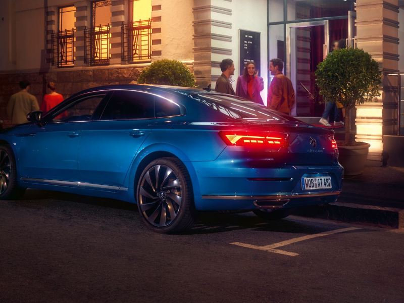 A blue New Arteon in a city street parking space.