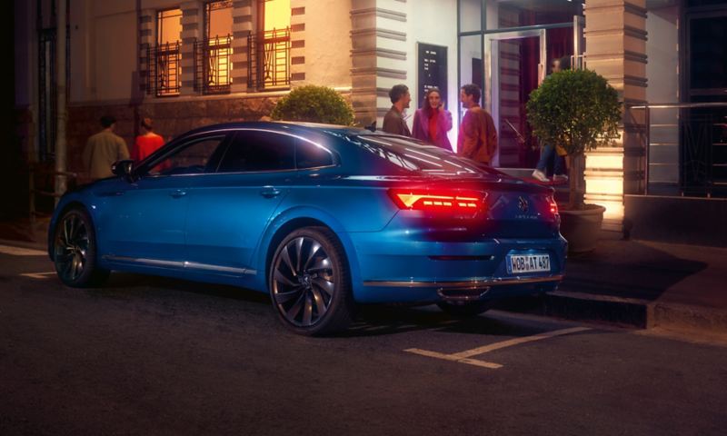 Three friends standing outside of a new Arteon