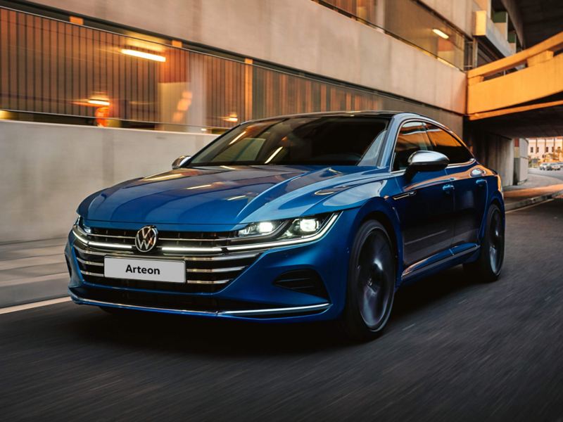 The new Arteon with front lights on driving along a road