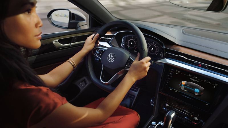Woman sitting at the steering wheel of the VW Arteon, looking at the steering wheel and touch display
