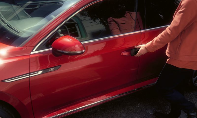 A person getting inside a red Arteon Shooting Brake car