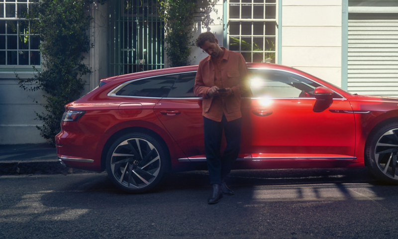 Man leaning on the Arteon Shooting Brake using his mobile phone