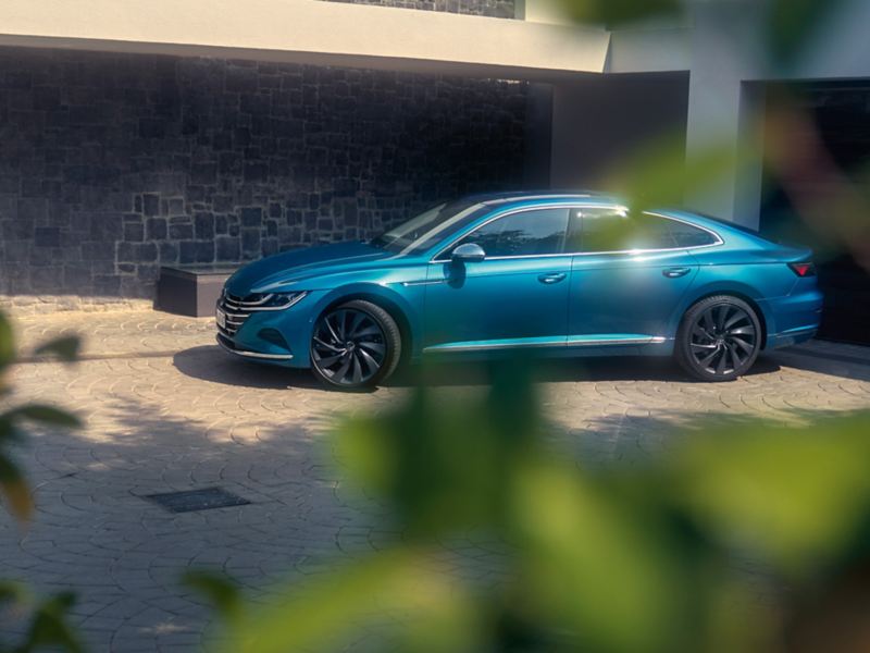 A blue new Arteon parked in front of a building
