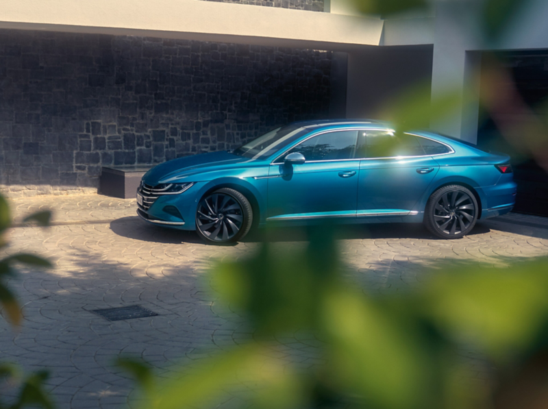 A blue new Arteon parked in front of a building