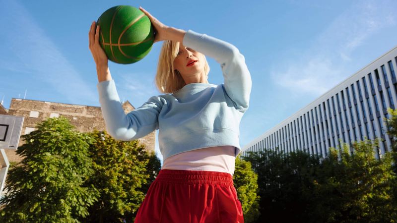 A lady holding a basketball on an outdoor basketball court