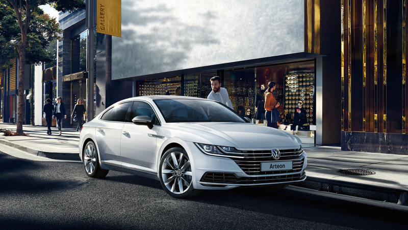 A man opening the door of a silver Arteon on a street