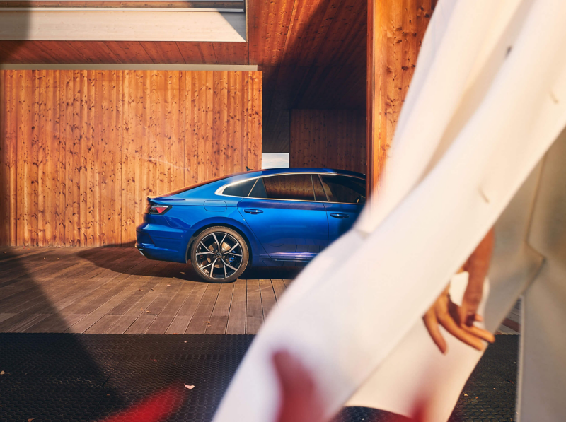 A blue VW R Arteon R stands under a carport