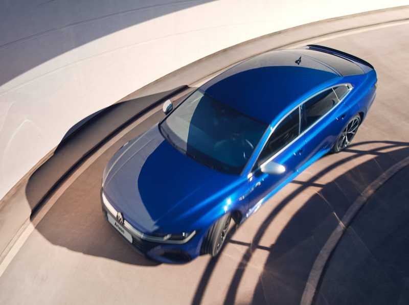 A blue Volkswagen Arteon R driving around a spiral car park