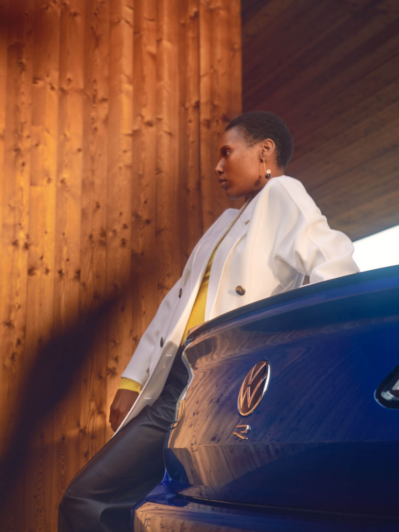 A woman leans against the rear of her VW Arteon R