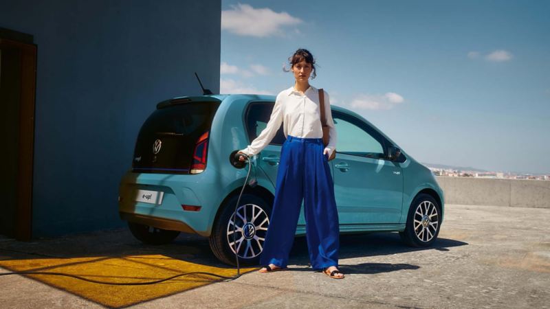 A lady plugging a charger into a blue VW e-up!