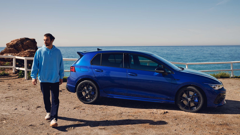  man walks away from his parked blue VWR Golf R “20 Years”