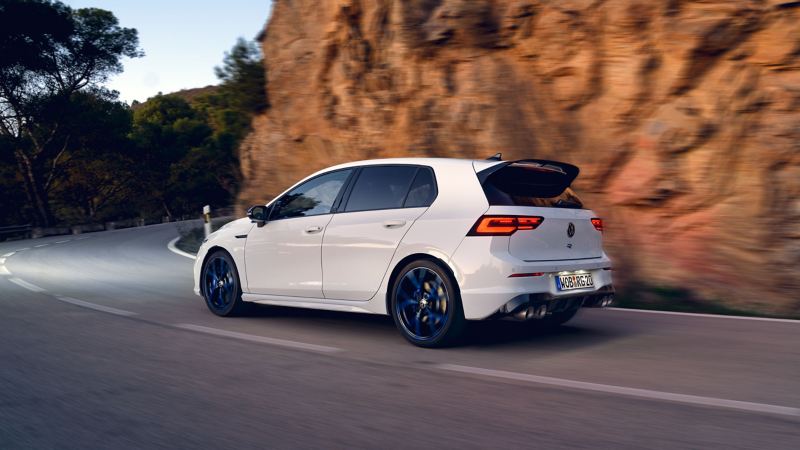 The white VWR Golf R “20 Years” drives along a road