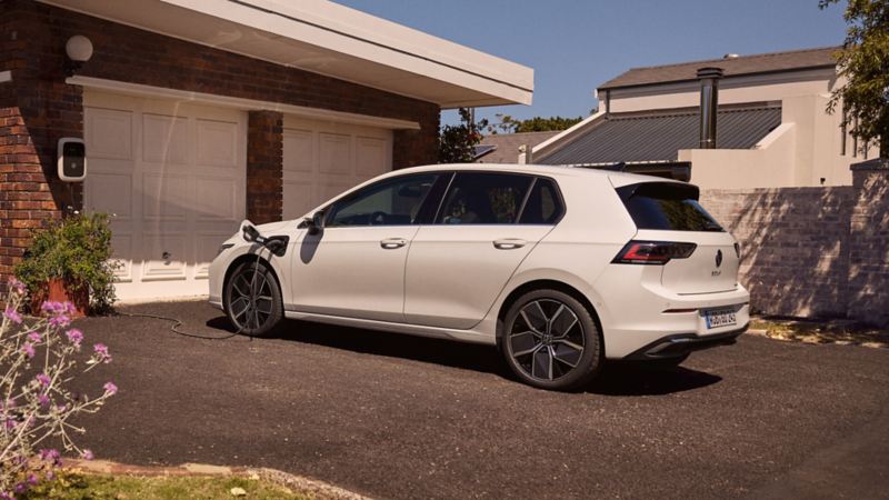 A white Volkswagen ID.7 parked in a driveway and plugged into a charger
