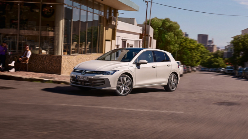 A white Golf driving past a cafe