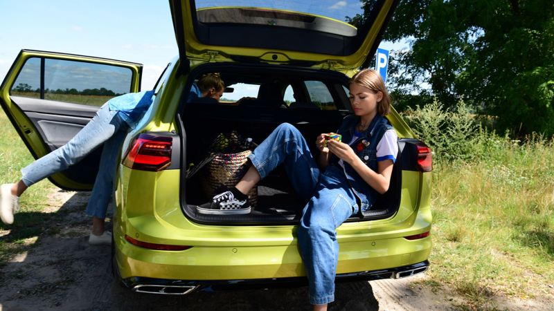 Girl sits in the open trunk of a Golf Variant
