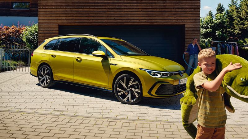 The New Volkswagen Golf Estate parked on a drive and a boy holding a cuddly toy