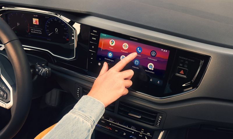 Display of the infotainment system in the VW Polo with We Connect functions Android Auto ™ from Google. A woman sits in the driver's seat and operates the display.