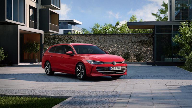 A red Passat stands in the courtyard of a modern residential complex in lateral perspective and with the front facing the viewer.
