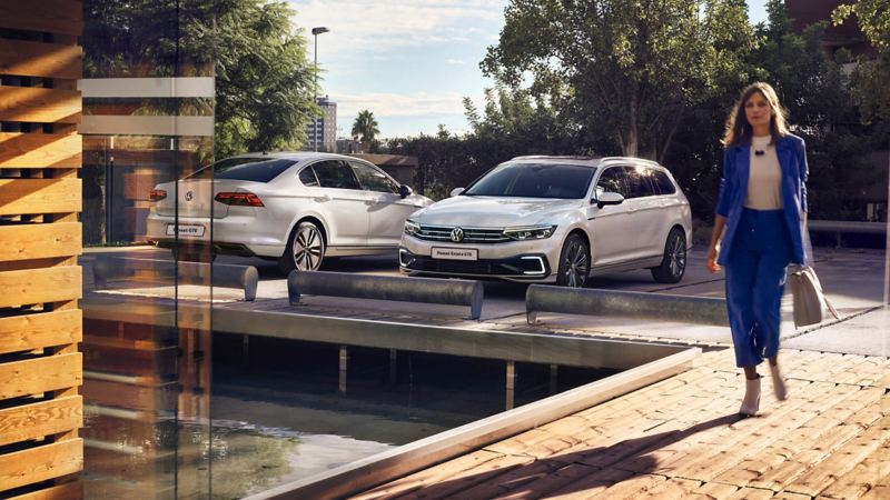 Woman walking past two parked Volkswagen Passat GTE parked outside an office