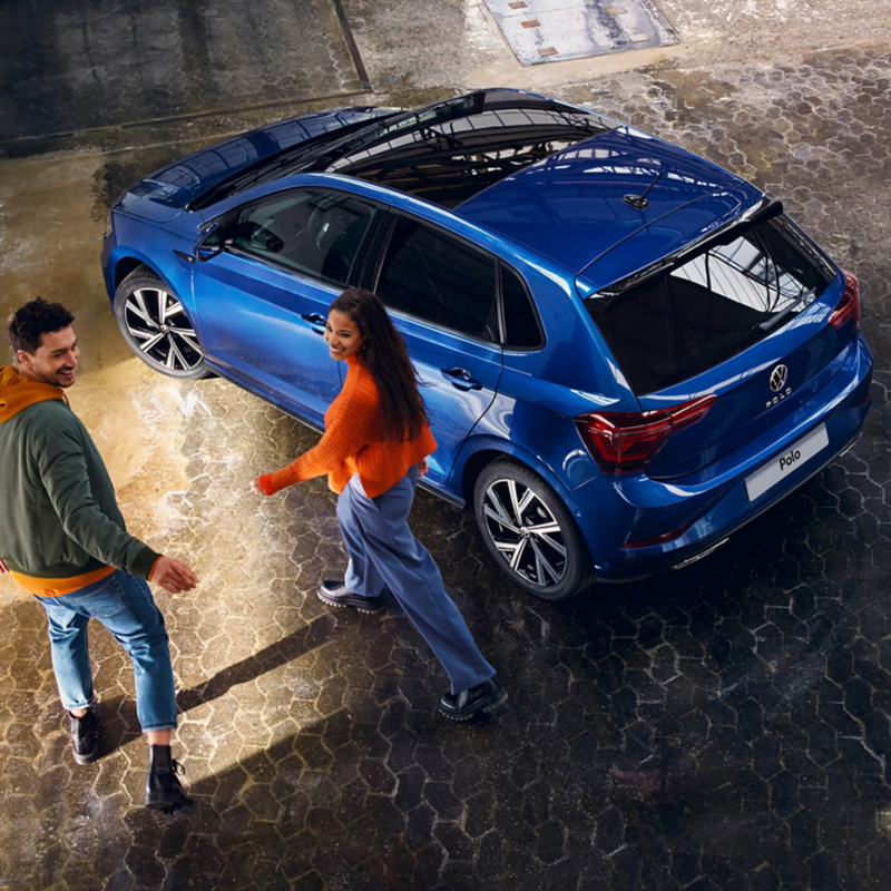 New VW Polo blue parked with two young people walking by