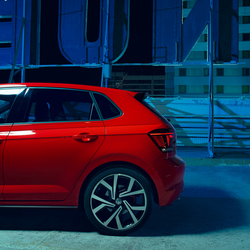 A side view of the rear half of a red Volkswagen Polo