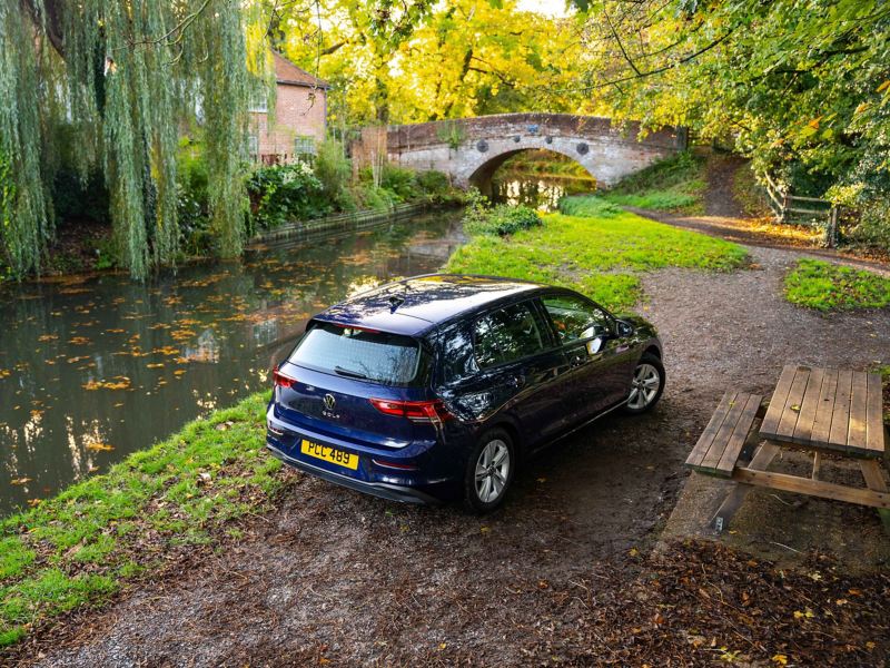 A Golf 8 parked next to a river and a picnic bench