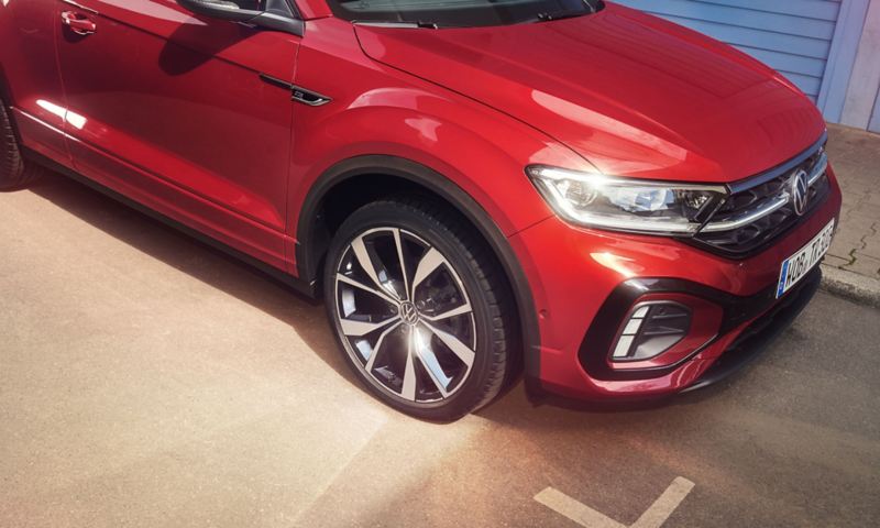 Lateral front of the red T-Roc Cabriolet with a view of the rims and headlights.